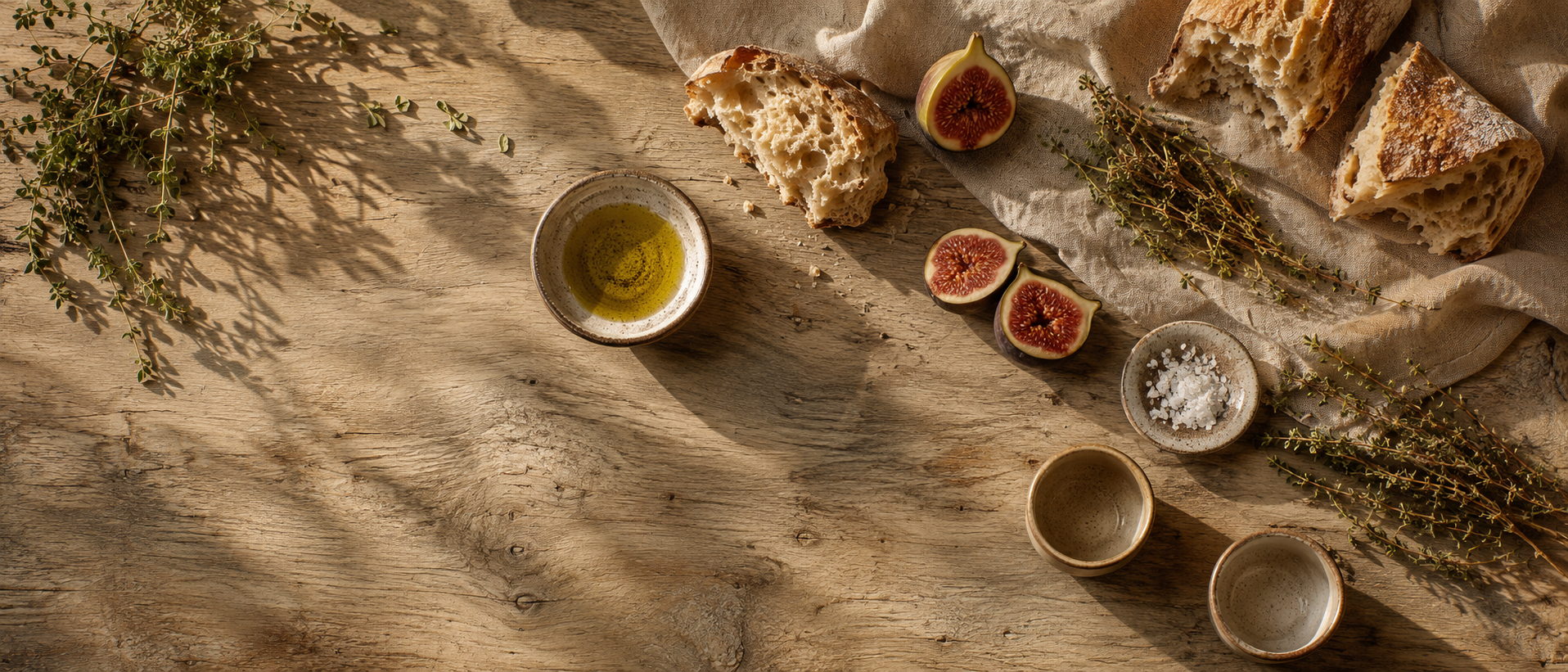 Gedeckter Tisch mit Olivenöl, Brot und Kräutern
